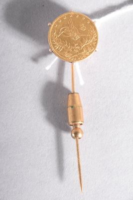 une pièce d'or posée sur un cure-dent, sur une surface blanche