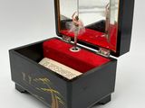 a black box with a ballerina in it on a white surface