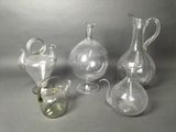 three clear glass vases and a glass teapot sitting on a table