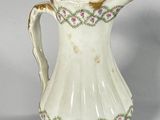 a white pitcher with pink flowers on it on a table