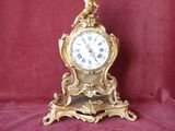 a gold clock with a bird on top of it