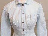 un mannequin vêtu d'une chemise bleu clair, posé sur un pied de mannequin