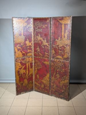un vieux paravent rouge et or orné de motifs asiatiques
