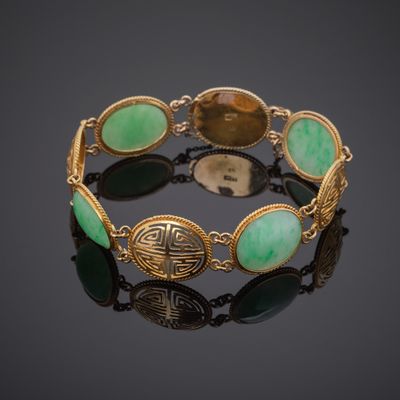 a close up of a bracelet with green stones on a black surface