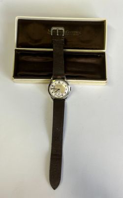 une image représentant une montre posée dans une boîte sur une surface blanche