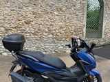 the blue scooter is parked in front of a stone wall
