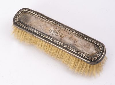 an antique silver plate brush with gold bristles on a white background