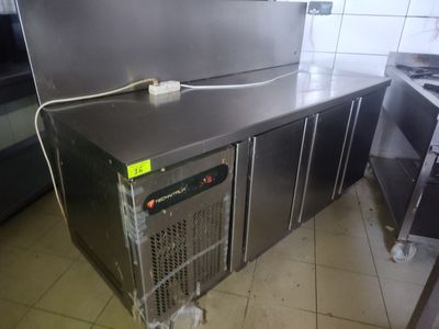 un plan de travail en acier inoxydable dans une cuisine professionnelle, sur lequel est posé un réchaud