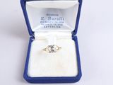 une photo d'une bague en diamant dans un écrin bleu posé sur une surface blanche