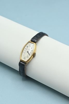 un gros plan d'une montre-bracelet posée sur une serviette de table, sur une table