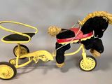a black horse pulling a yellow tricycle with a red seat