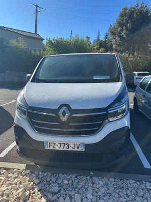 une camionnette blanche garée sur un parking à côté d'une voiture bleue