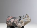 une figurine de rhinocéros posée sur une surface blanche