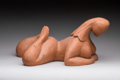 une photo d'une sculpture en argile représentant un chien couché sur le flanc