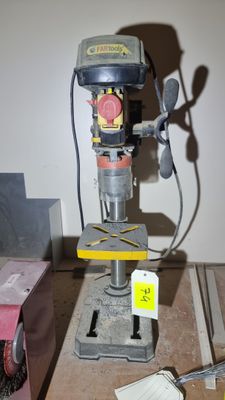 une perceuse posée sur une table sur laquelle se trouvent de nombreux outils