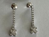 two pairs of diamond earrings on a white background with a price tag