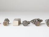 several different types of silver and silver jewelry on a white surface