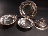 three silver dishes on a black table with a black background