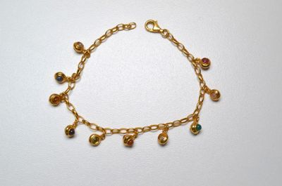 a close up of a gold bracelet with bells on it