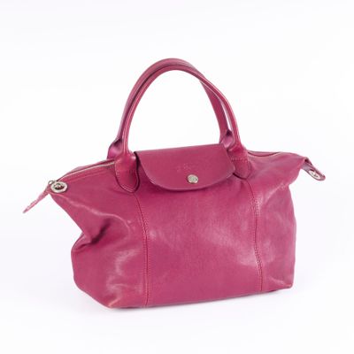 the pink leather handbag is sitting on a white surface