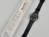 La montre est noire et est dotée d'un bracelet en cuir noir.
