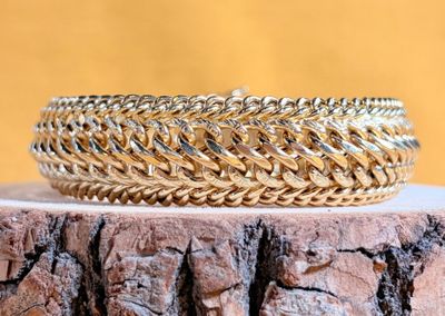 un gros plan d'un bracelet en or posé sur une souche d'arbre