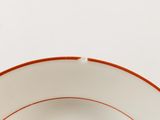 a white plate with a red rim and a brown rim
