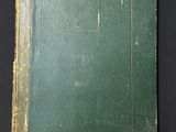 an old green book sitting on top of a black table