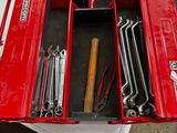 une boîte à outils rouge remplie d'outils, posée sur une table