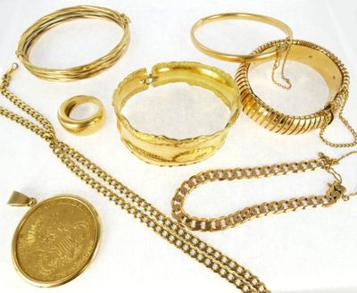 a lot of gold bracelets and rings on a table