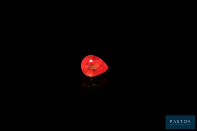a red heart shaped diamond sitting on top of a black surface