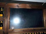 a television mounted on a wall with bottles of wine