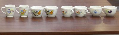 six coffee mugs lined up on a wooden table