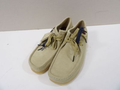 chaussures bateau de couleur beige clair avec des lacets bleus sur un fond blanc