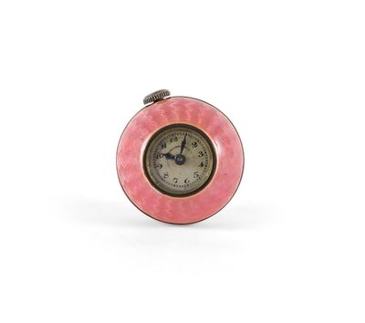 horloge avec un cadran rose sur fond blanc, posée sur une surface blanche