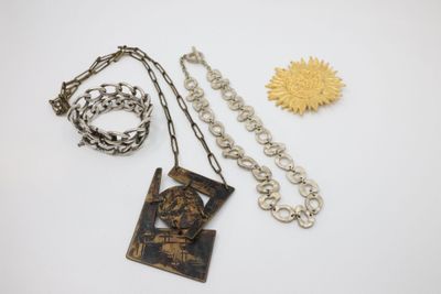 a close up of a necklace, bracelet, and brooch on a white surface