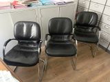 three black leather office chairs sitting in a room