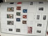 une personne tenant une grande feuille de papier sur laquelle sont collés des timbres