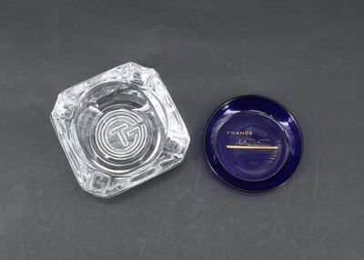 un gros plan d'un cendrier en verre et d'un cendrier bleu posés sur une table