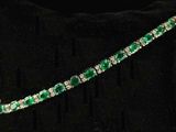 a close up of a green and white bracelet on a black pillow