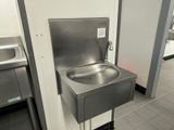 a stainless steel sink in the middle of a public restroom