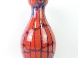 a red and blue vase sitting on a white surface