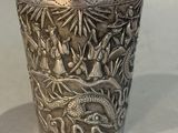 a silver cup sitting on a table with a dragon on it