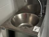 a stainless steel sink in the corner of a public restroom