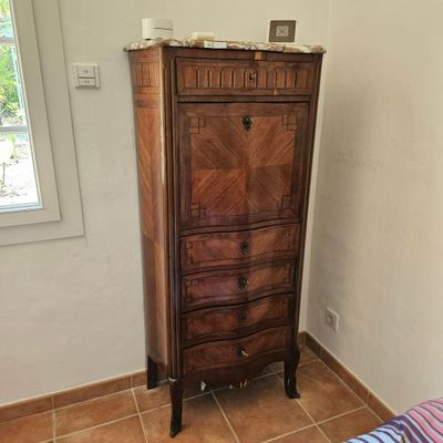 une commode dans un coin d'une chambre où se trouve un lit