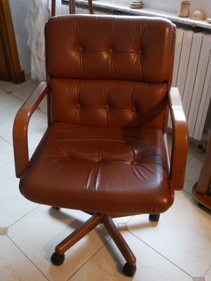 une chaise de bureau en cuir marron placée dans un coin de la pièce