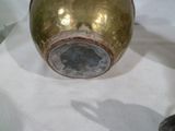 un vase doré posé sur une table blanche