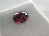 a close up of a red garnet stone on a white surface