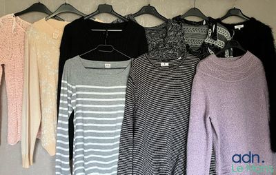 many sweaters hanging on a clothes rack in a closet