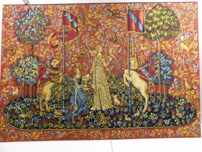 La tapisserie est accrochée au mur d'une pièce où se trouve le portrait d'une femme et de deux chiens.